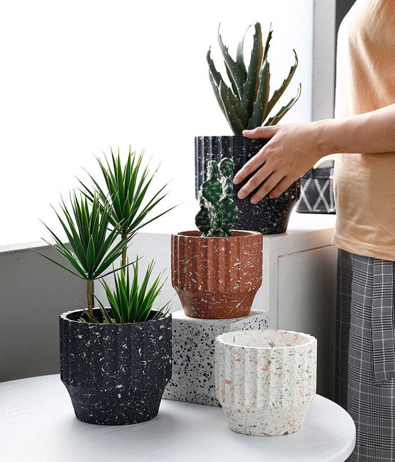 a woman holding a potted plant on top of a white table